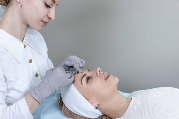 Woman receiving facial treatment from dermatologist with microneedle device