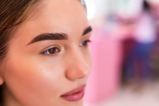 Close-up of a young woman with detailed eyebrows in a colorful setting